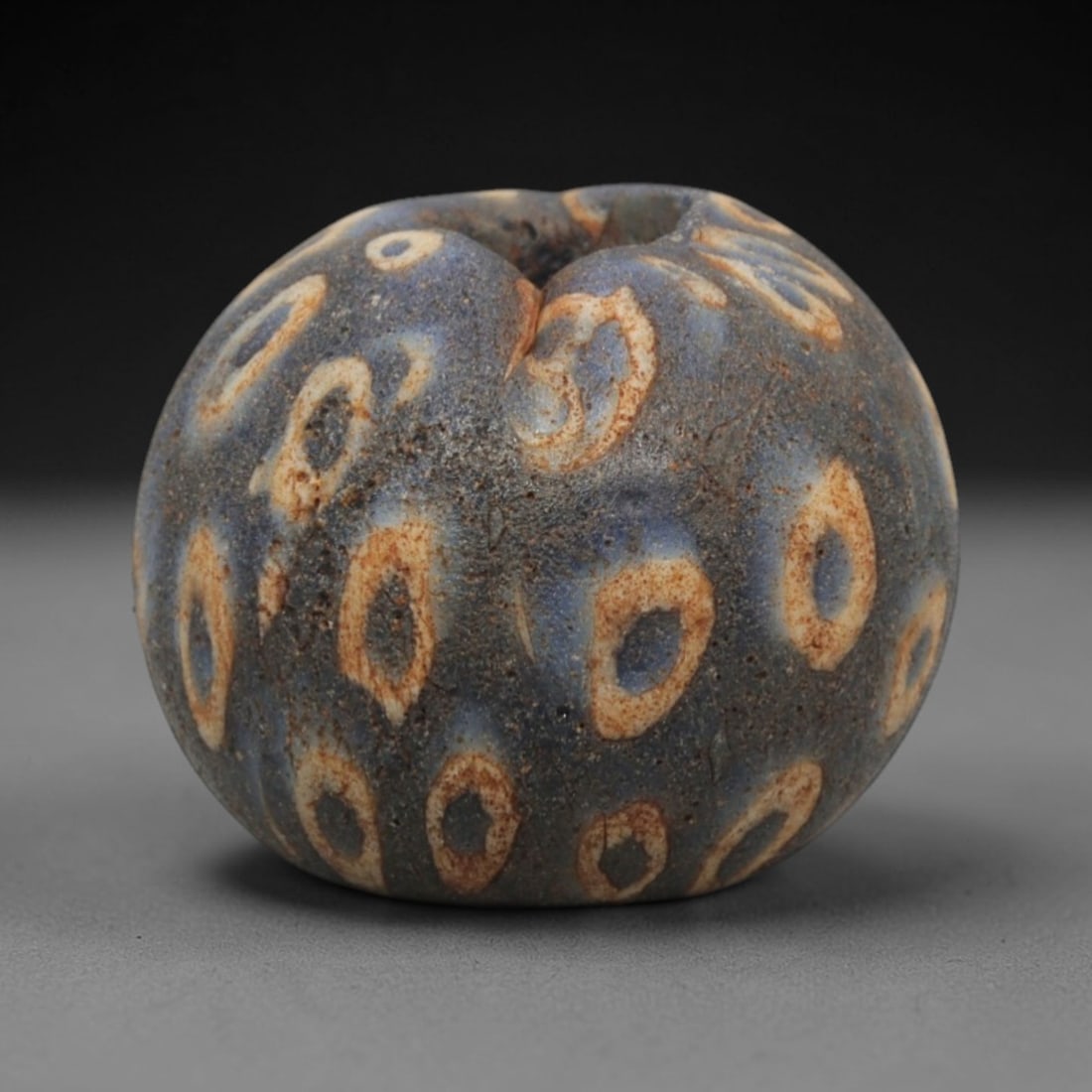 Ancient Glass Bead - Roman Egyptian Dragonfly Eye Amulet, 57ZN: Crafted from opaque glass with polychrome inlay, this spherical bead features a central suspension hole and is decorated with repeating concentric circle motifs, known as "dragonfly eyes," in white, y