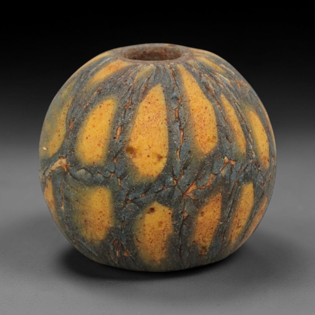Ancient Islamic Glass Bead - Swirled Mosaic Trade Bead, 75ZN: Crafted from ancient glass, this Islamic period bead features a swirled mosaic pattern with layered yellow, red, and white glass trails applied to a translucent base, characteristic of decorative glas