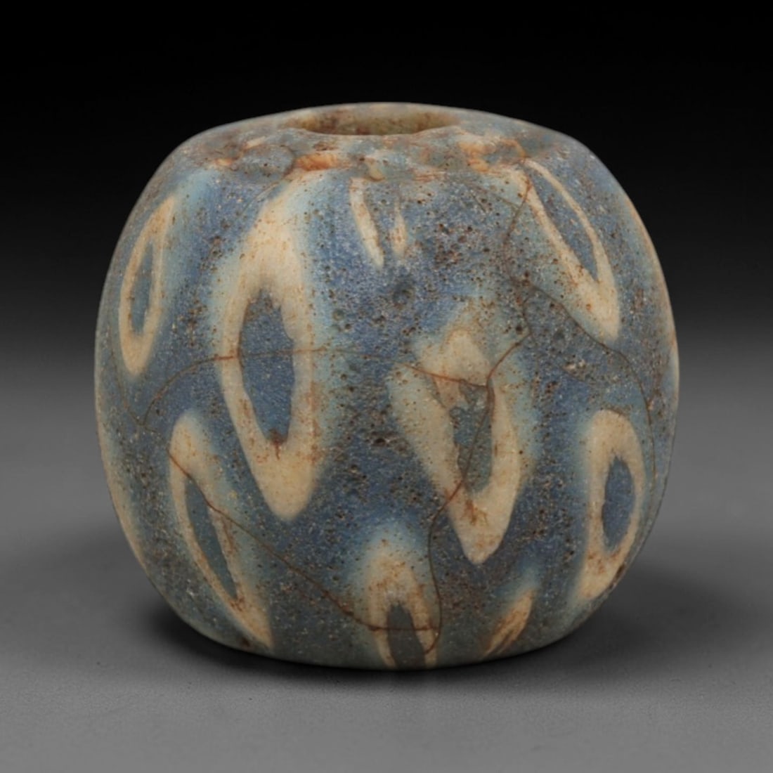 Ancient Glass Bead - Roman Egyptian Swirl Pattern Amulet, 79ZN: Crafted from opaque glass with a delicate swirling loop pattern in cream against a muted blue matrix, this barrel-shaped bead features a central suspension hole for wear as an amulet. The decorative t