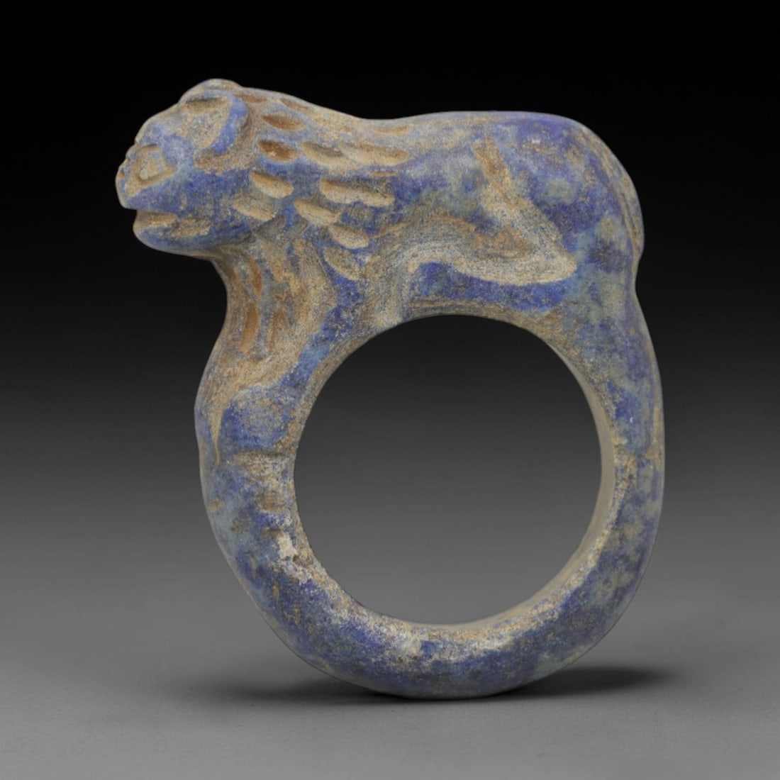Ancient Lapis Lazuli Ring - Achaemenid Feline Signet Ring, 40ZQ: Carved from lapis lazuli, this ancient Achaemenid ring features a stylized feline head motif with linear detailing, characteristic of Achaemenid glyptic art. The ring exhibits a smooth, aged patina co
