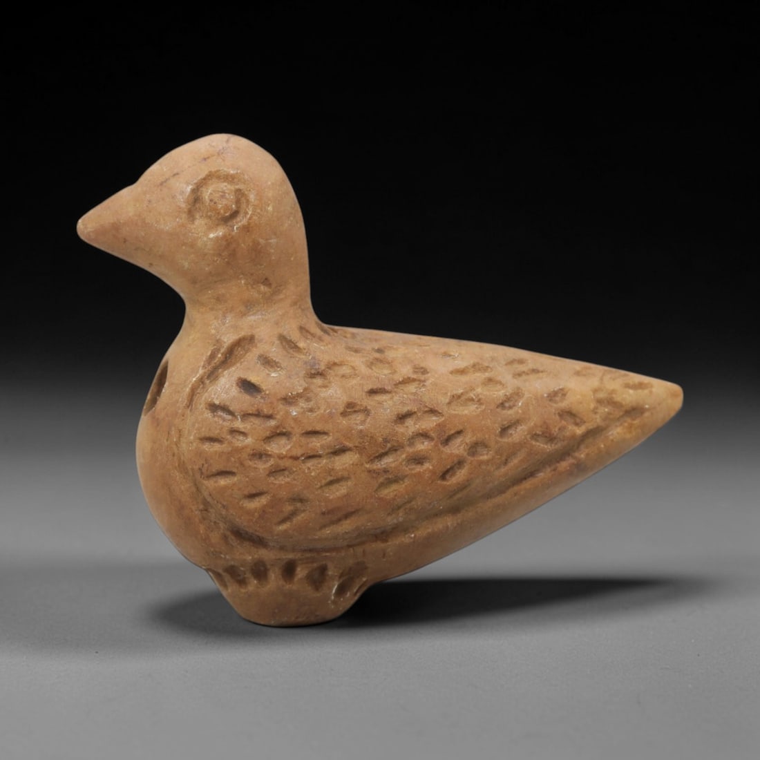 Ancient Steatite Bird Amulet - Near Eastern Carved Figurine, 69ZQ: Carved from steatite, this ancient Near Eastern bird amulet features a compact, stylized avian form with detailed facial features and a textured body surface. The carving exhibits primitive yet expres