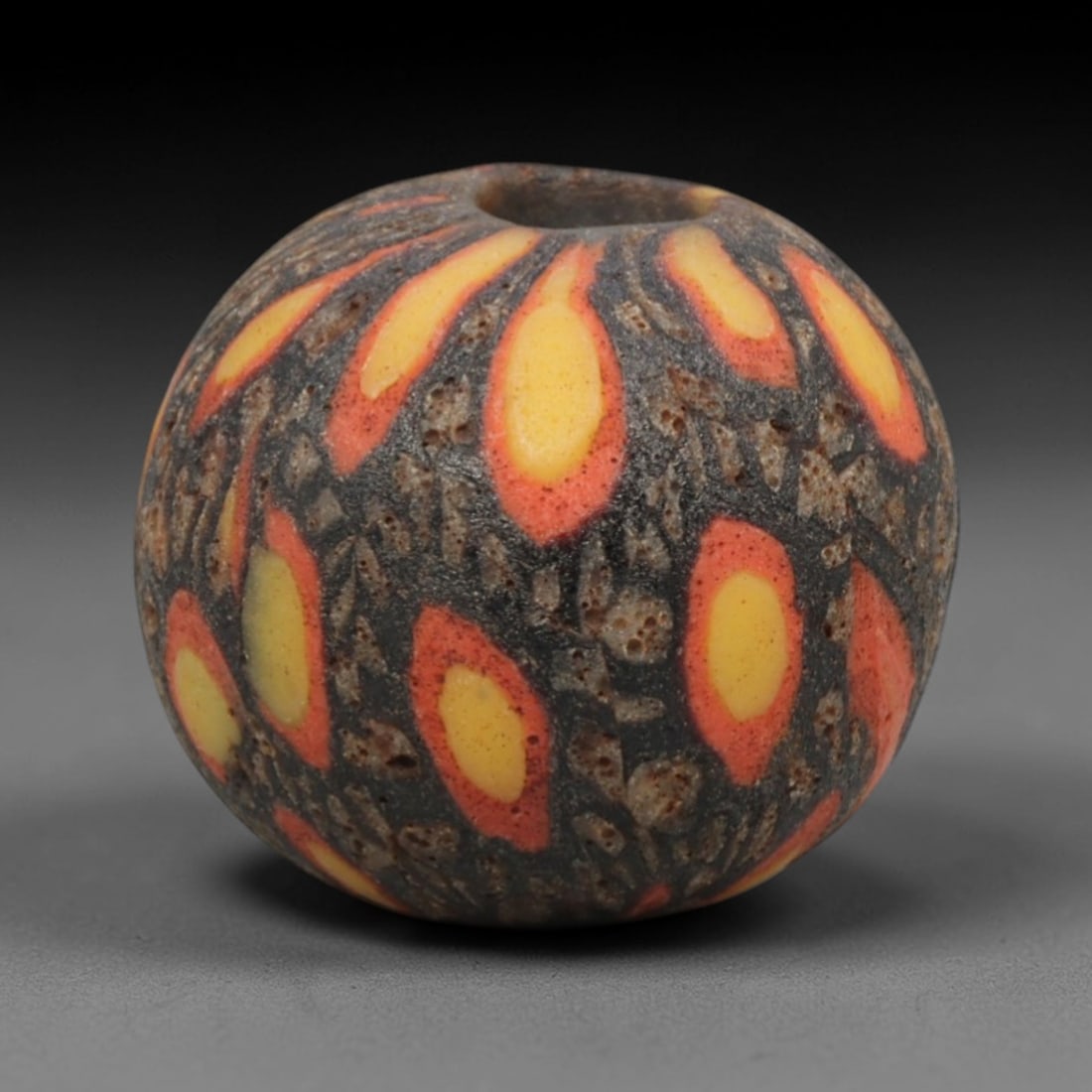 Ancient Glass Bead - Roman Egyptian Teardrop Mosaic Amulet, 49ZN: Crafted from mosaic glass, this spherical bead features a central suspension hole and is decorated with repeating teardrop-shaped motifs in yellow, red, and dark brown glass inlay, characteristic of R