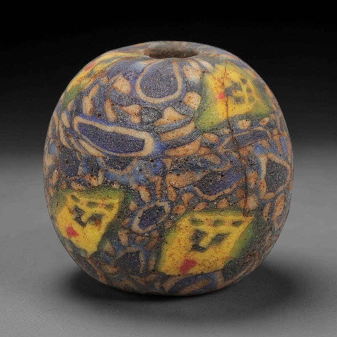 Ancient Glass Bead - Roman Egyptian Mosaic Amulet, 81ZN: Crafted from mosaic glass, this bead exhibits the intricate polychrome inlay characteristic of Roman-Egyptian glassworking techniques from the Early Roman Imperial period. The spherical form features