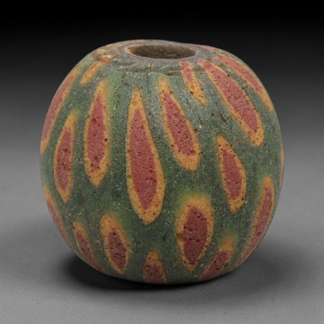 Ancient Islamic Glass Bead - Swirled Mosaic Trade Bead, 38ZN: Crafted from ancient glass, this Islamic period bead features a swirled mosaic pattern with layered yellow, red, and green glass trails applied to a translucent base, characteristic of decorative glas