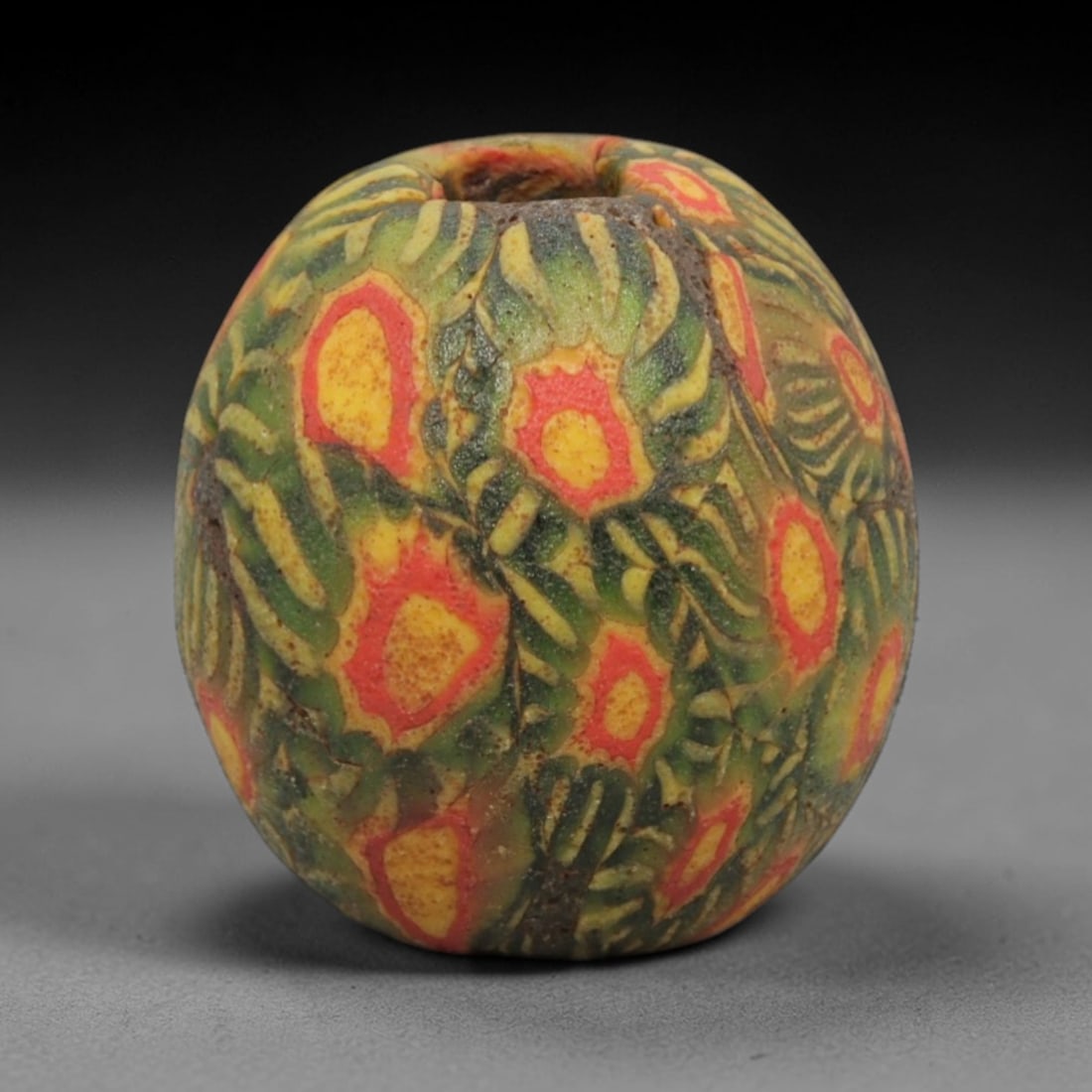 Ancient Islamic Glass Bead - Floral Mosaic Trade Bead, 54ZN: Crafted from ancient glass, this Islamic period bead features a floral mosaic pattern with layered yellow, red, and green glass trails applied to a translucent base, characteristic of decorative glass