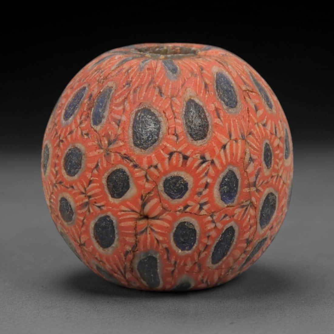 Ancient Islamic Glass Bead - Mosaic Eye Trade Bead, 91ZN: Crafted from ancient glass, this Islamic period bead features a mosaic eye pattern with layered red, blue, and white glass trails applied to a translucent base, characteristic of decorative glassmakin