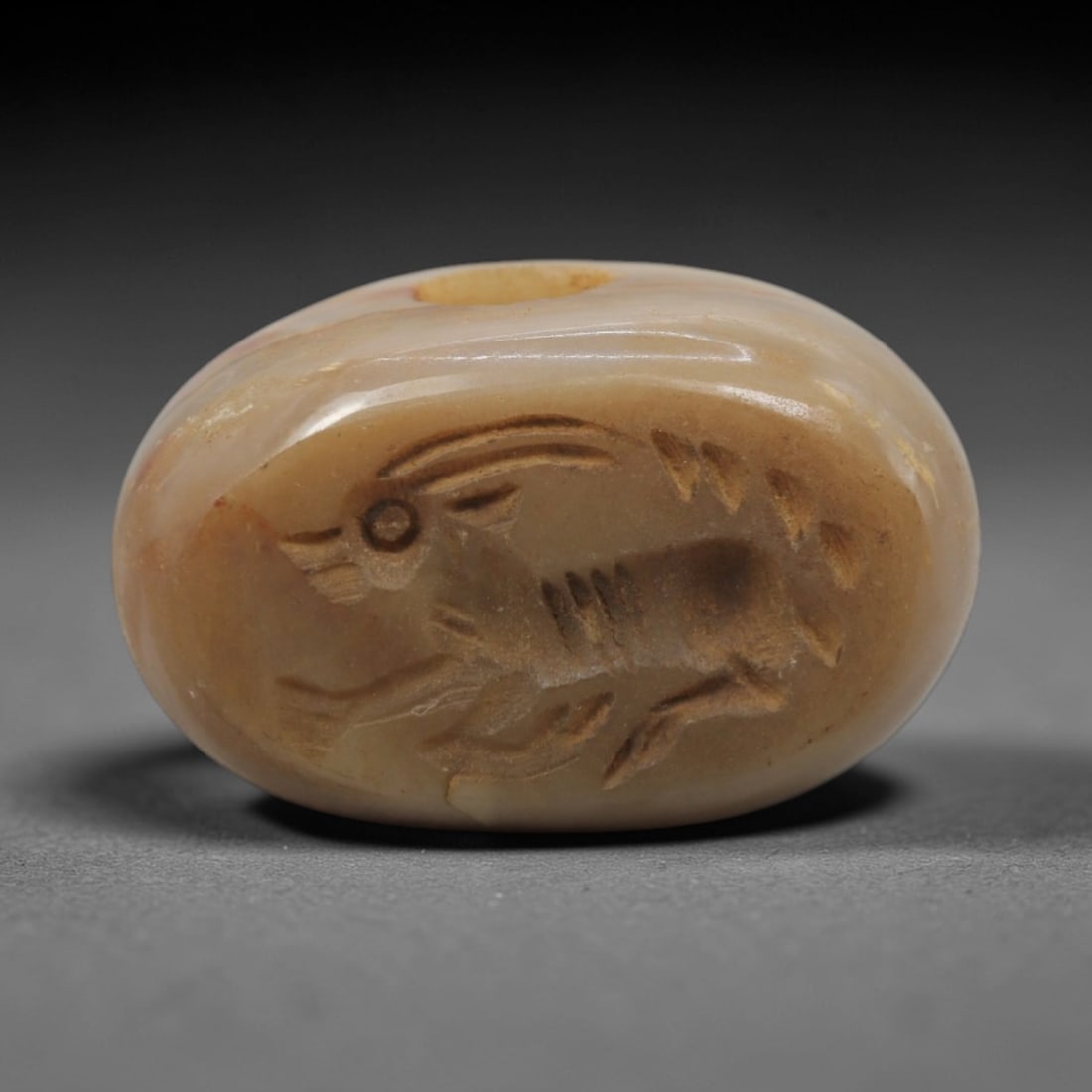 Ancient Steatite Stamp Seal - Near Eastern Amulet, 55ZQ: Carved from steatite, this small stamp seal features a stylized running stag motif with incised linear detailing on the upper face. The stone exhibits a soft, earthy patina with minor surface wear con