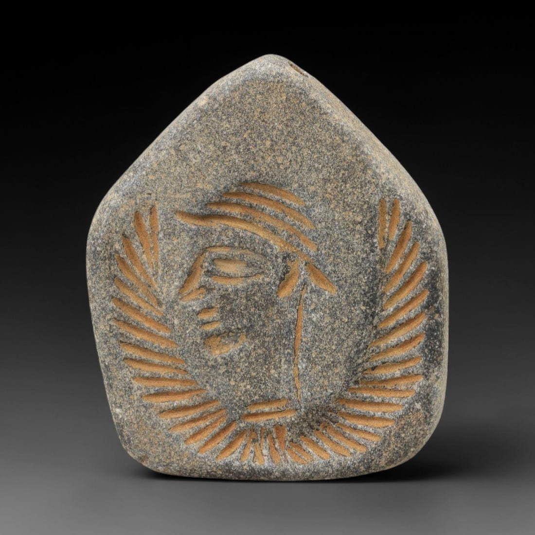 Ancient Steatite Amulet - Near Eastern Figurine Pendant, 8AJ: Carved from steatite stone, this ancient Near Eastern amulet features a stylized human head with a crown-like headdress and detailed facial features. The carving exhibits primitive yet expressive craf