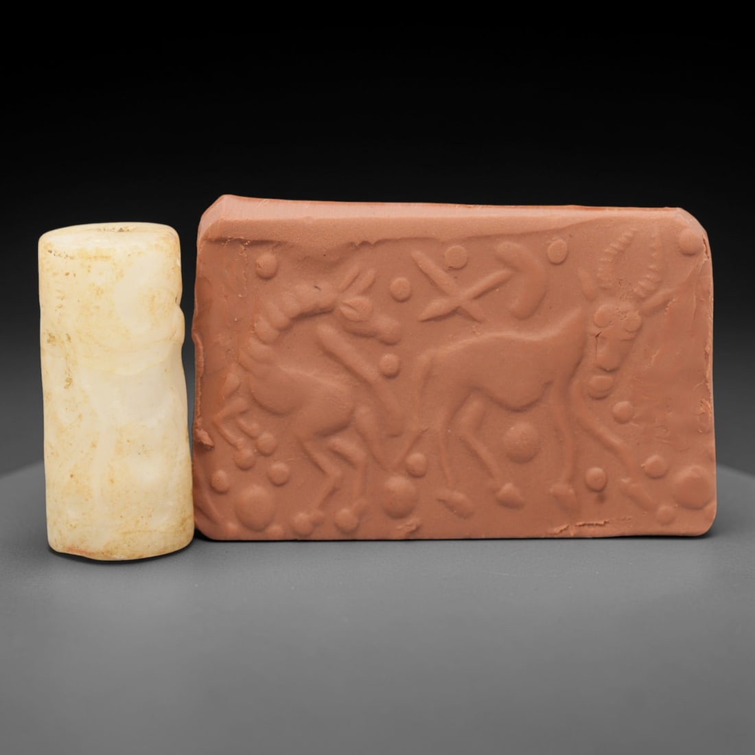 Ancient Calcite Cylinder Seal - Near Eastern Glyptic Art, 83ZQ: Carved from calcite stone, this ancient Near Eastern cylinder seal features a cylindrical form with raised relief carvings depicting stylized bovine figures and geometric patterns. The seal exhibits f