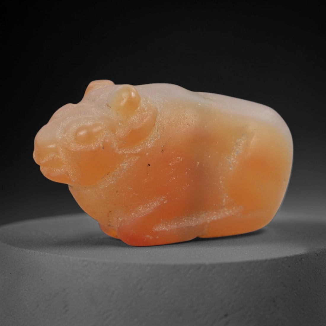 Ancient Carnelian Bovid Amulet - Near Eastern Figurine, 40AJ: Carved from warm orange carnelian, this amulet is formed as a stylized recumbent bovid (likely a bull or ram) with rounded horns, a distinct snout, and compact body, consistent with ancient Near Easte
