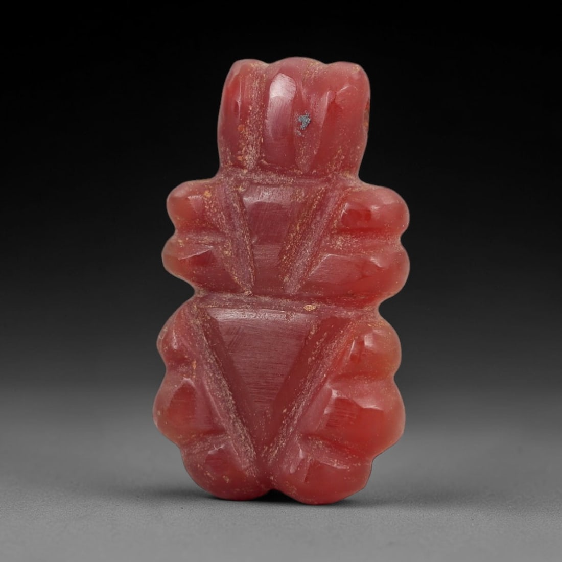 Ancient Carnelian Insect Amulet - Near Eastern Figurine, 31AJ: Carved from vibrant red carnelian, this amulet is formed as a stylized insect with segmented body lobes and incised linear detailing across the torso to denote anatomical structure. A suspension hole 