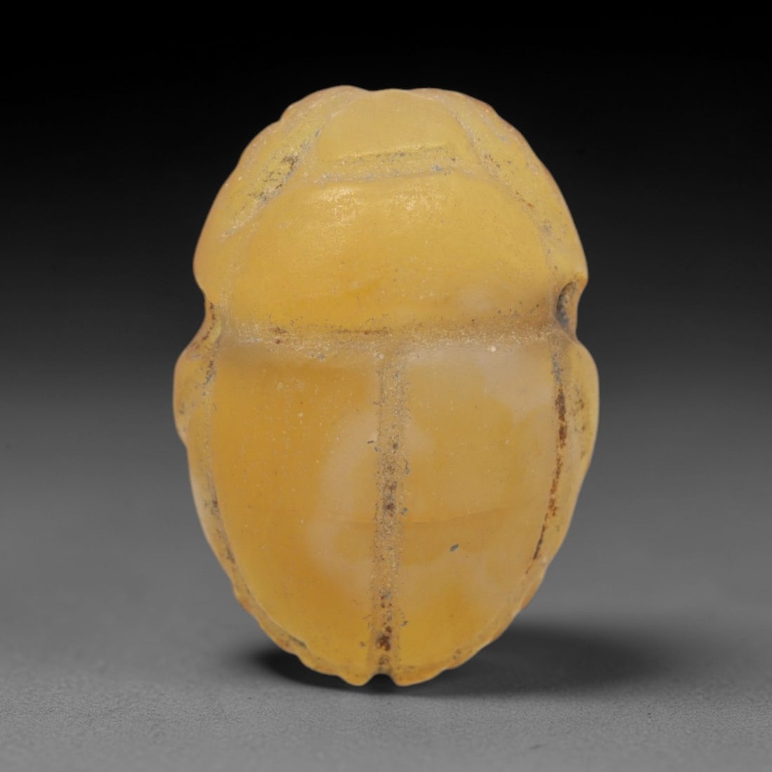 Ancient Agate Scarab - Egyptian Amulet Bead, 66XS: This amulet is carved from translucent yellowish-agate, exhibiting natural banding and a warm, glossy finish characteristic of ancient Egyptian glyptic craftsmanship. The form is a classic scarab beet