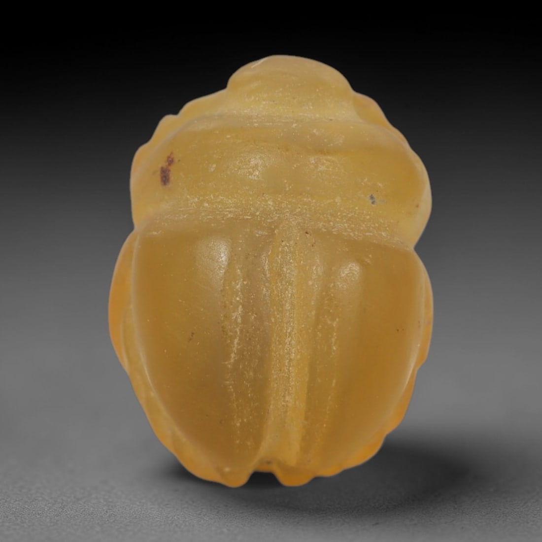 Ancient Chalcedony Scarab Amulet - Egyptian Figurine, 51XS: Carved from smooth, pale yellow chalcedony with natural surface inclusions and subtle tonal variations, this amulet is formed as a stylized scarab beetle with incised linear detailing to define the ce