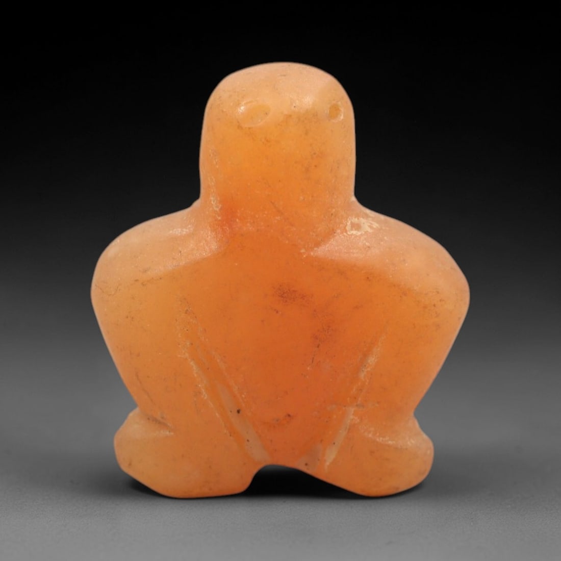 Ancient Agate Bird - Near Eastern Figurine Amulet, 65XS: This amulet is carved from warm orange agate, exhibiting natural translucency and subtle banding characteristic of ancient Near Eastern glyptic craftsmanship. The form is a stylized avian figure, with