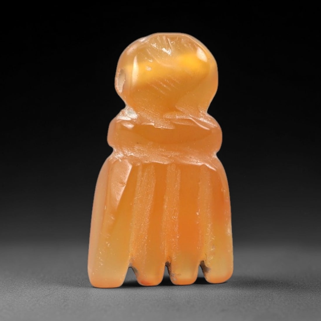 Ancient Carnelian Fist - Egyptian Protective Amulet, 47XS: Carved from translucent, warm amber carnelian with natural surface patination and subtle wear, this amulet takes the form of a clenched fist, featuring a rounded knuckle section at the top and distinc