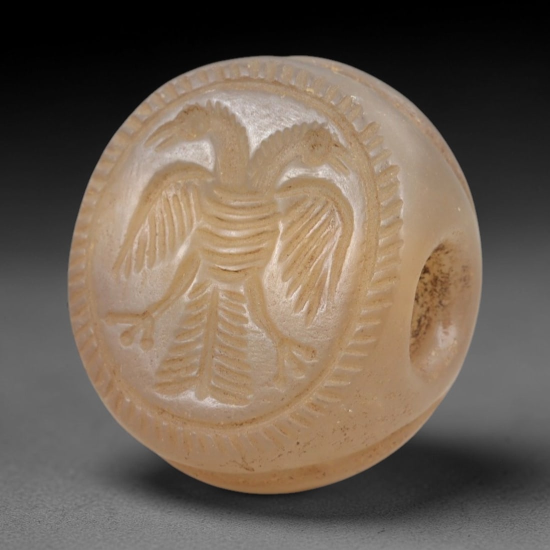 Ancient Chalcedony Stamp Seal - Sasanian Double-Headed Eagle, 59AK: Carved from translucent chalcedony, this hemispherical Sasanian stamp seal features a central double-headed eagle motif with outstretched wings, ribbed torso, and detailed feathering, encircled by a r