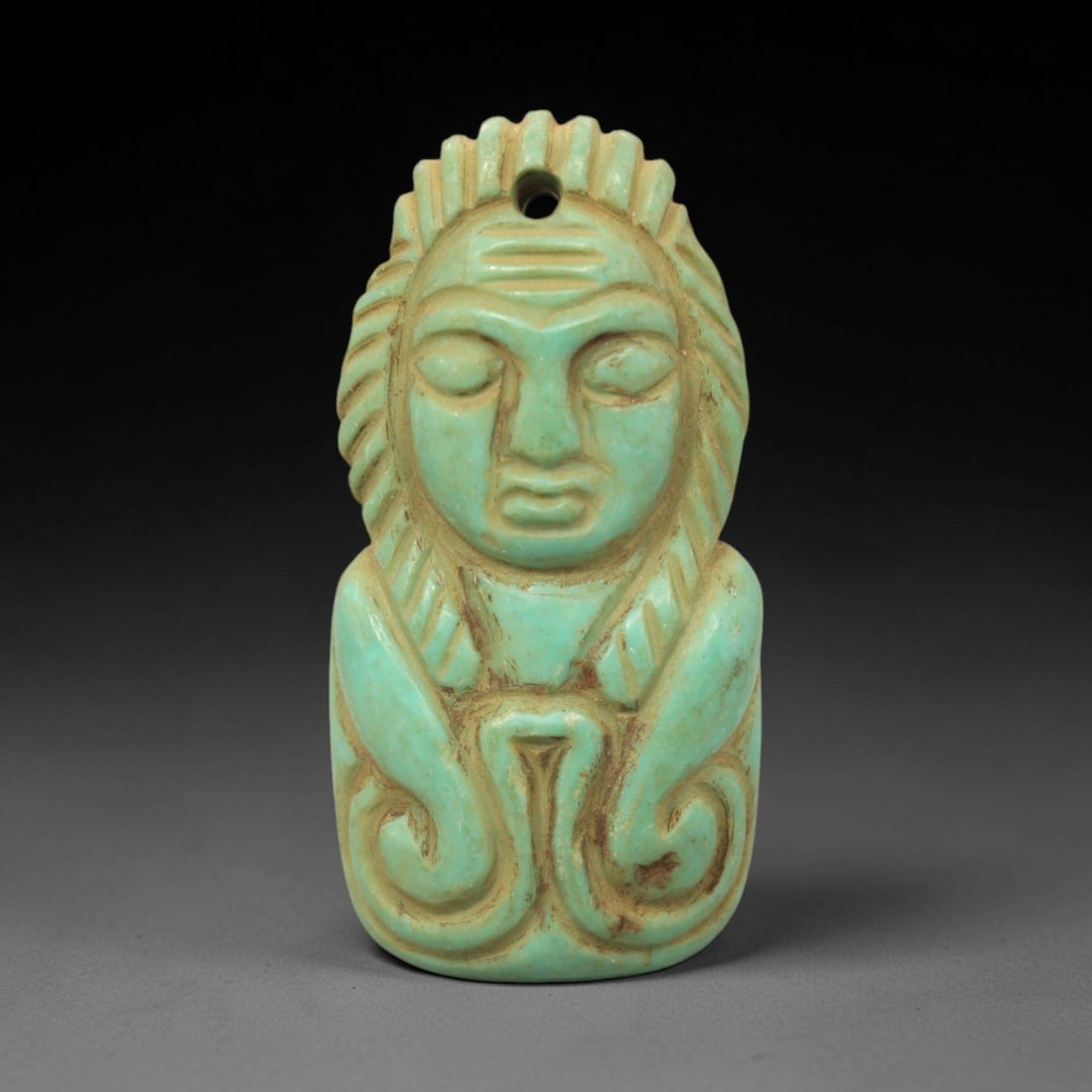 Ancient Turquoise Anthropomorphic Amulet - Near Eastern Figurine, 6XV: Carved from turquoise, this amulet depicts a stylized anthropomorphic figure with closed eyes, a serene facial expression, and incised striations representing hair or a headdress. A perforation at the