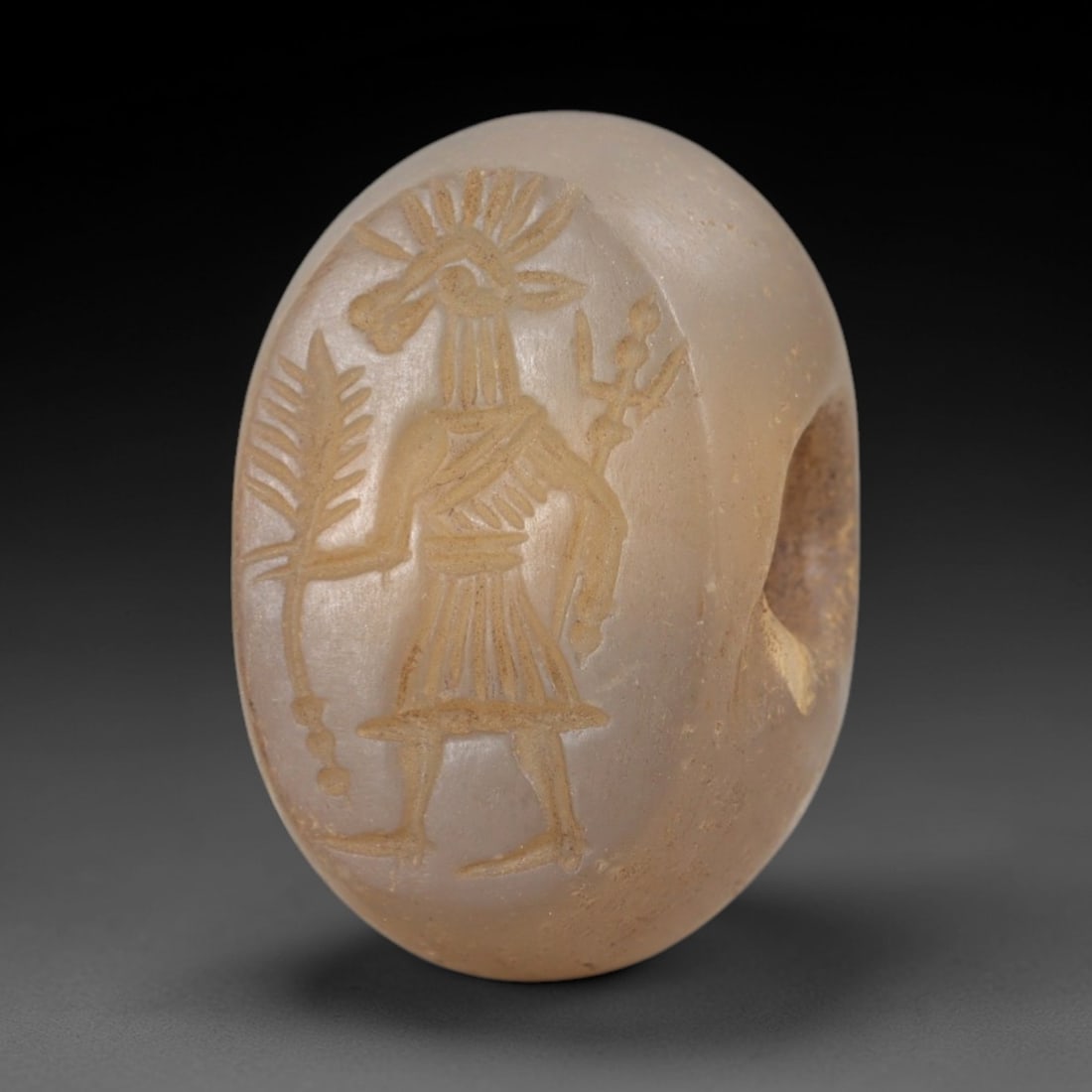 Ancient Chalcedony Stamp Seal - Sasanian Anthropomorphic Deity, 61AK: Carved from translucent chalcedony, this oval Sasanian stamp seal features a central anthropomorphic deity figure with an animal-headed crown, holding a palm frond and a ritual scepter, consistent wit