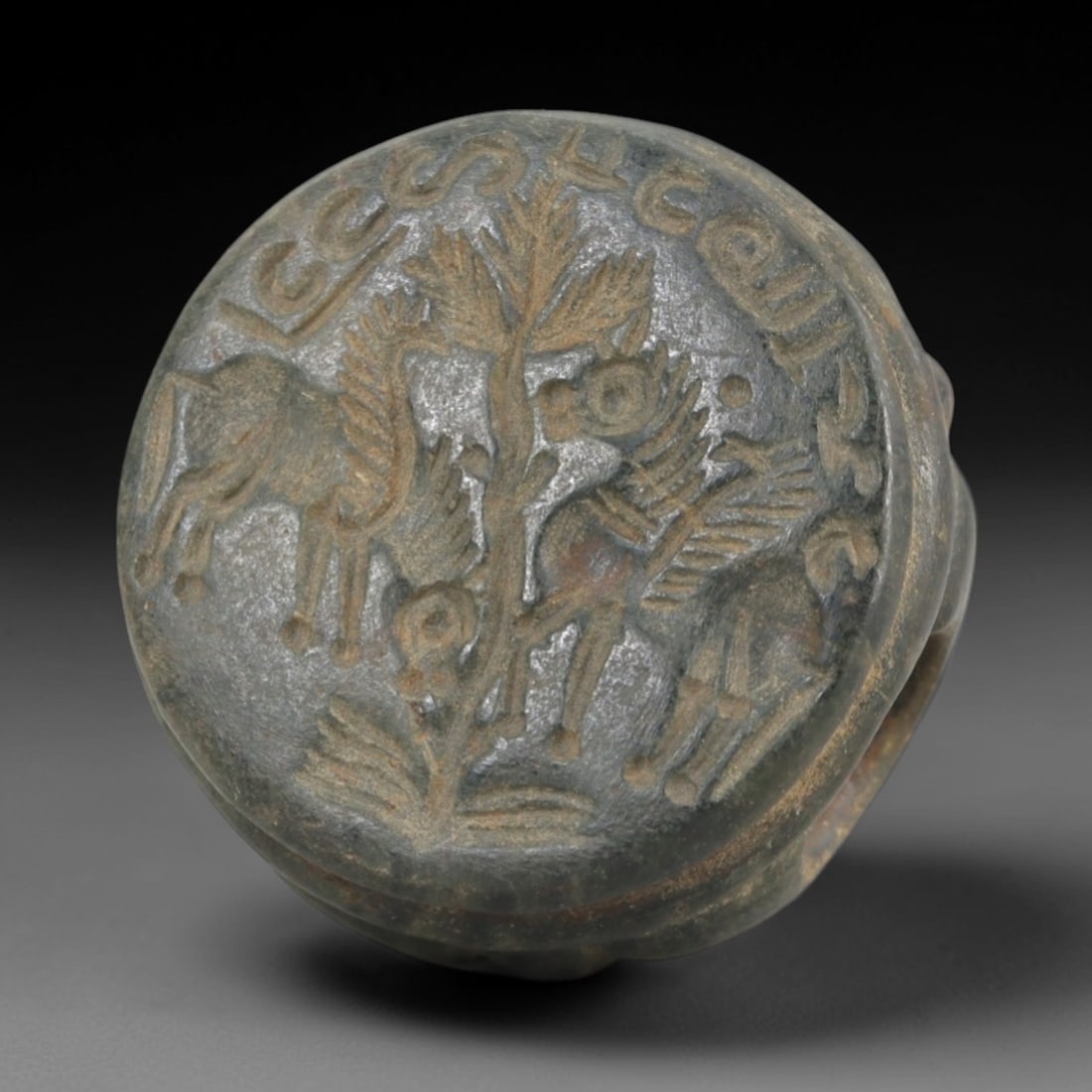 Ancient Steatite Stamp Seal - Sasanian Winged Horses, 56AK: Carved from steatite, this hemispherical Sasanian stamp seal features a central composition of two winged horses flanking a stylized tree motif, with incised epigraphic script encircling the iconograp