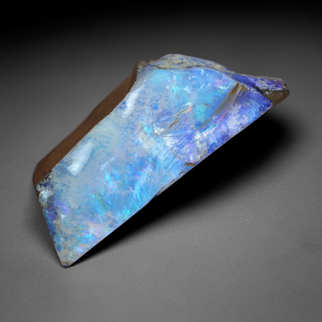 12.94 Carats Iridescent Blue-Purple Winton Opal Rough - Natural Australian Specimen 22x8mm, 78XM: This exceptional rough opal from Winton, Australia, captivates with a vivid play of color, where intense flashes of celestial blue and delicate lavender-purple swirl through a milky, translucent base.
