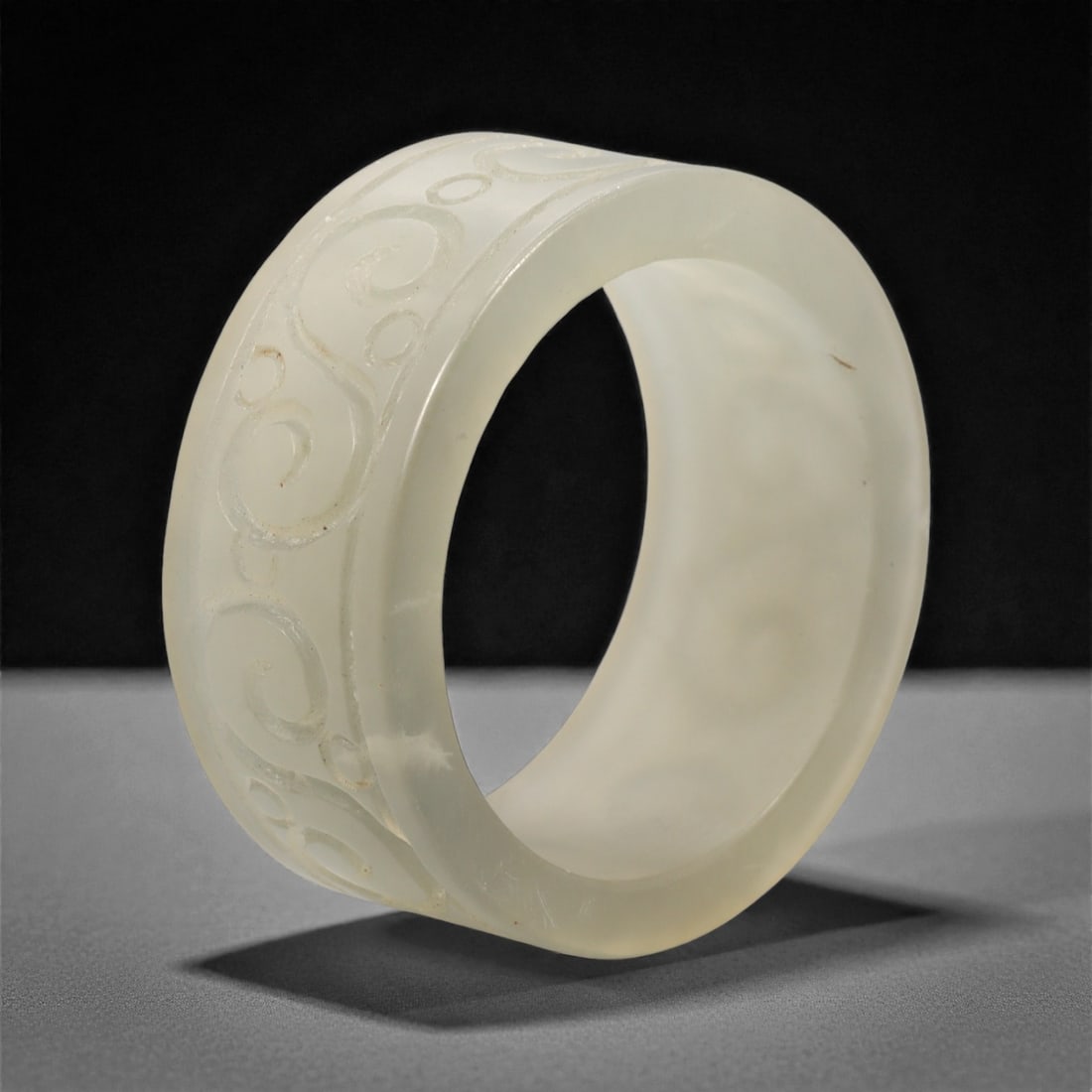 A Chinese Hetian Jade Cylindrical Ornament, 20th Century, 66FH: Carved from pale creamy-white Hetian jade with soft translucency and minor natural inclusions, the object is formed as a thick-walled cylinder with a circular aperture and evenly rounded rims. The ext