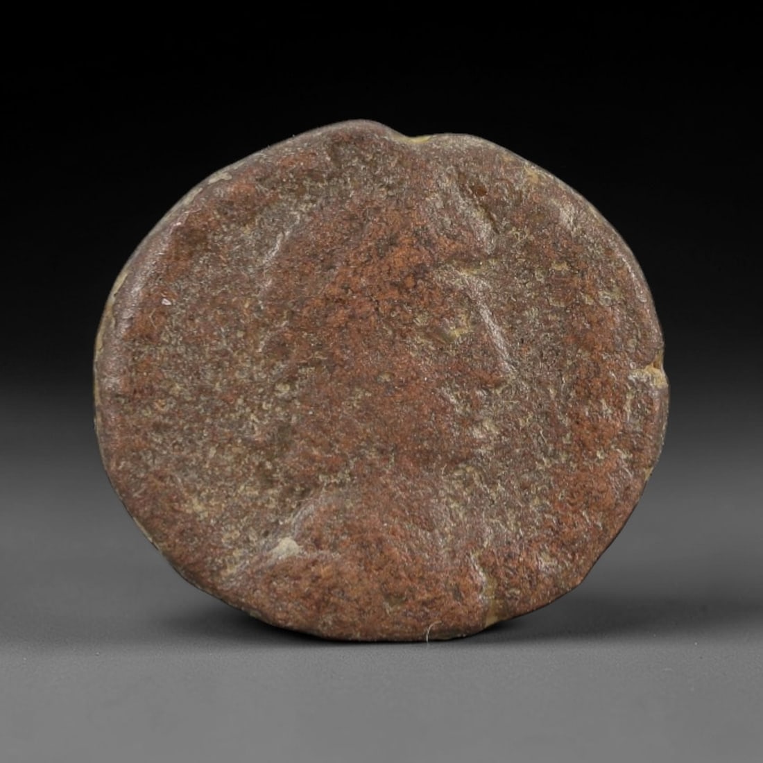 An Ancient Roman Bronze Coin, 1st-4th Century, 62FW: Cast from bronze with a naturally aged, patinated surface and subtle brown and greenish corrosion, the coin is circular in form, with a profile bust on the obverse and a standing figure on the reverse
