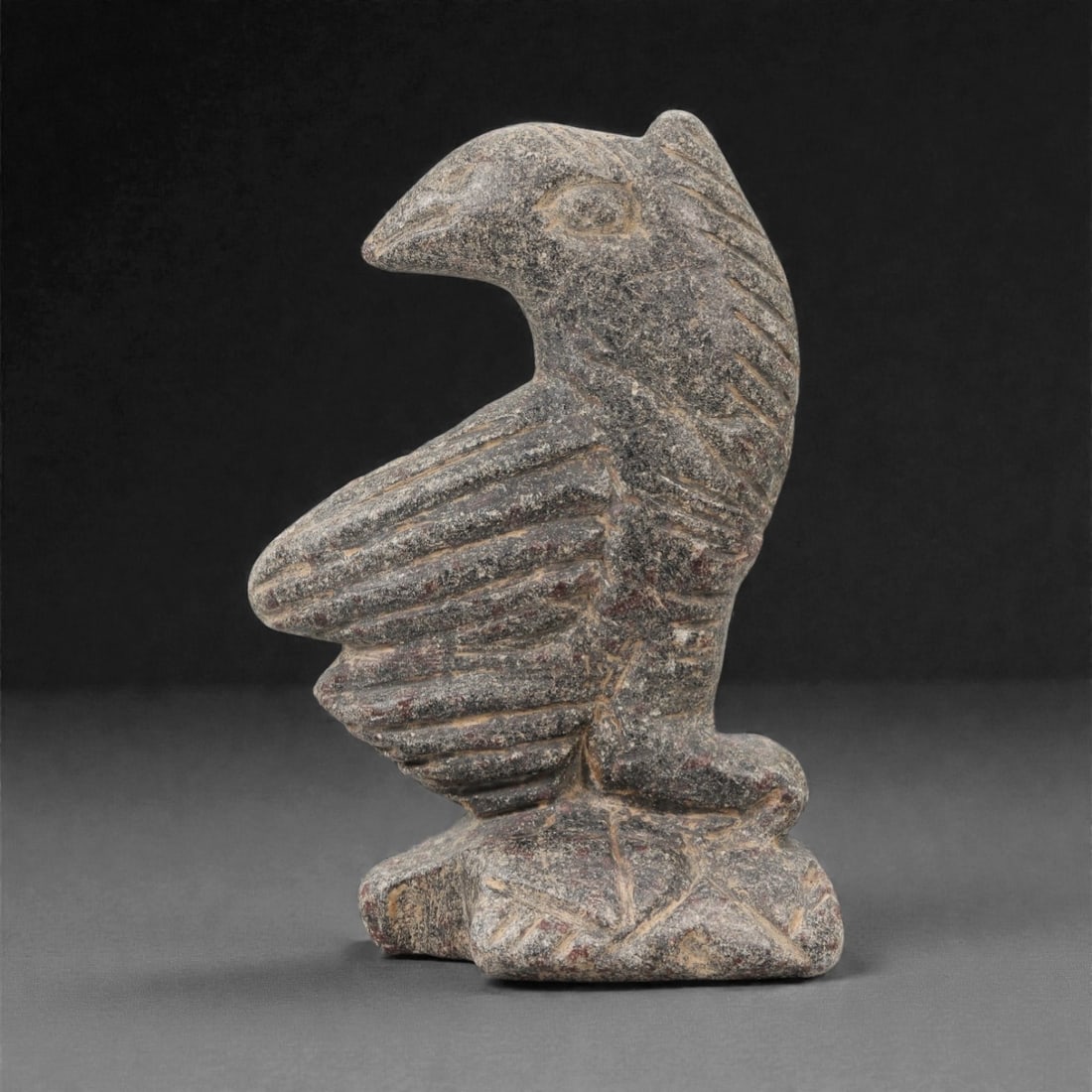 A Near Eastern Stone Bird Effigy, 3rd-2nd Millennium BCE, 2FM: Carved from grey stone with natural surface patination and reddish-brown incised decoration, the object is formed as a stylized avian figure in a standing pose. The head is rendered in low relief with