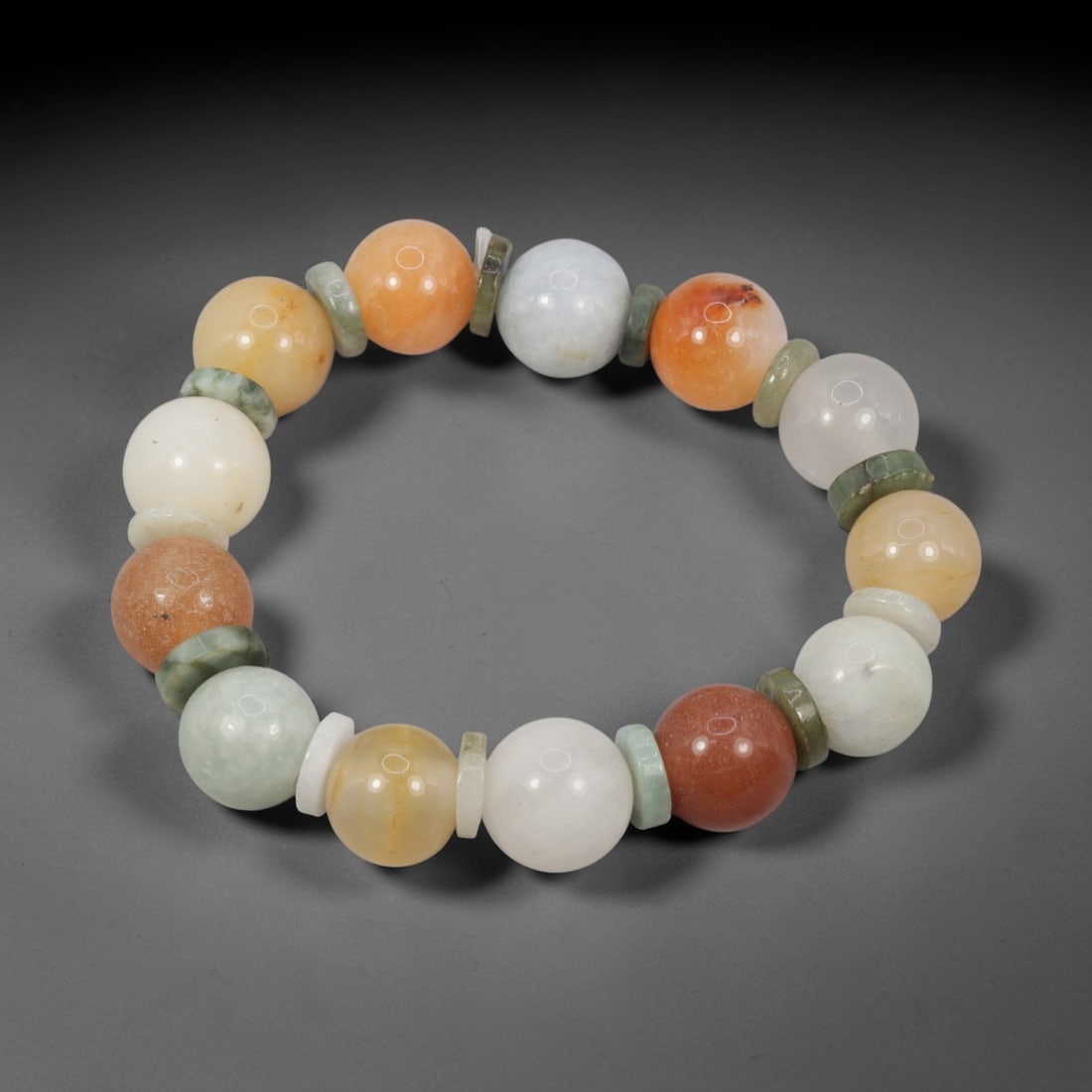 A Chinese Jadeite Jade Bead Bracelet, 20th Century, 90FS: Composed of spherical beads of multicolored jadeite jade, including pale celadon, orange, red, yellow, and white, with natural veining and minor internal inclusions, the bracelet is strung in a contin