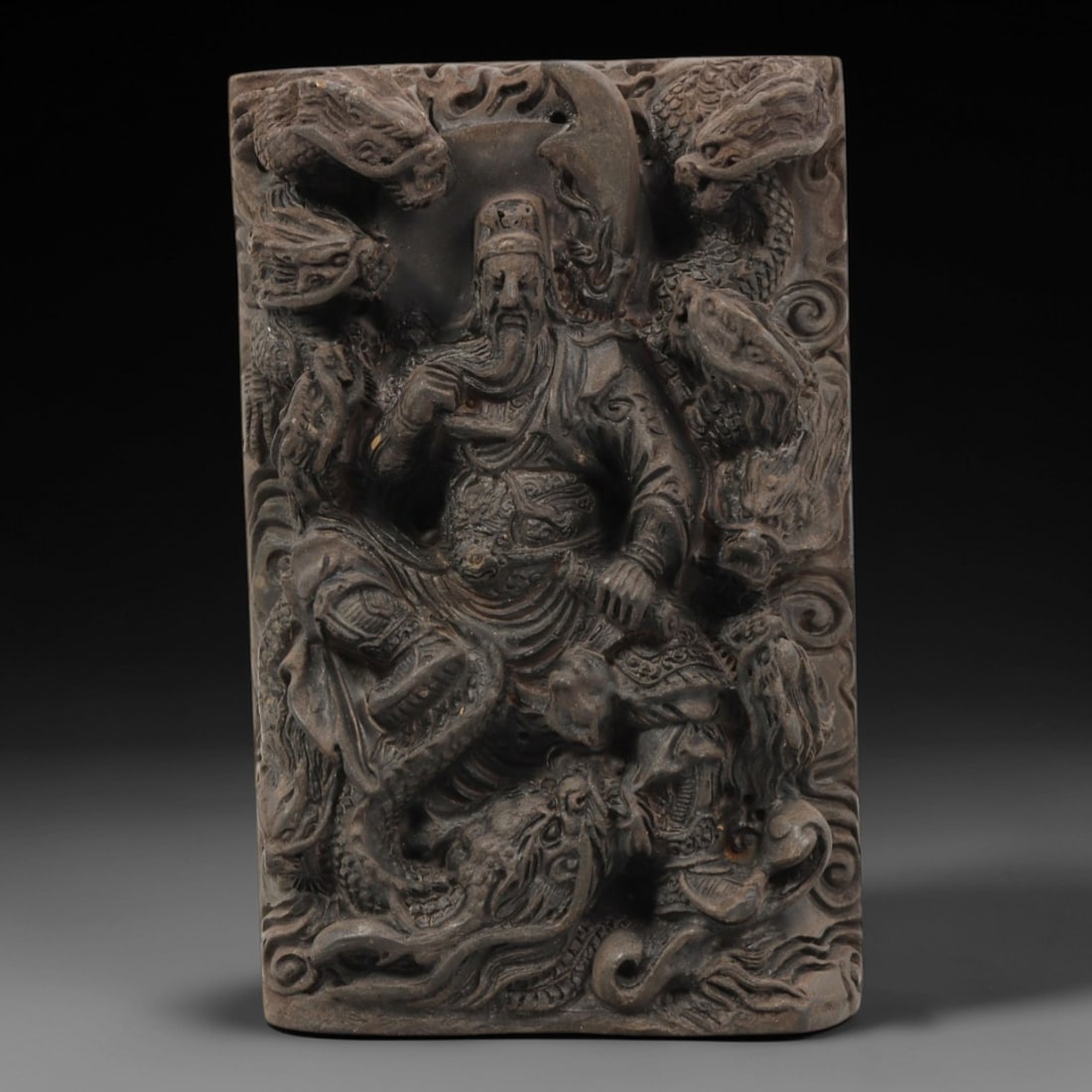 A Chinese Horn or Bone Guandi and Dragon Plaque, 20th Century, 87FV: Carved from horn or bone with a naturally aged, patinated surface and subtle tonal variations, the plaque is rectangular in form, depicting Guandi seated amidst multiple coiled dragons. Guandi is rend