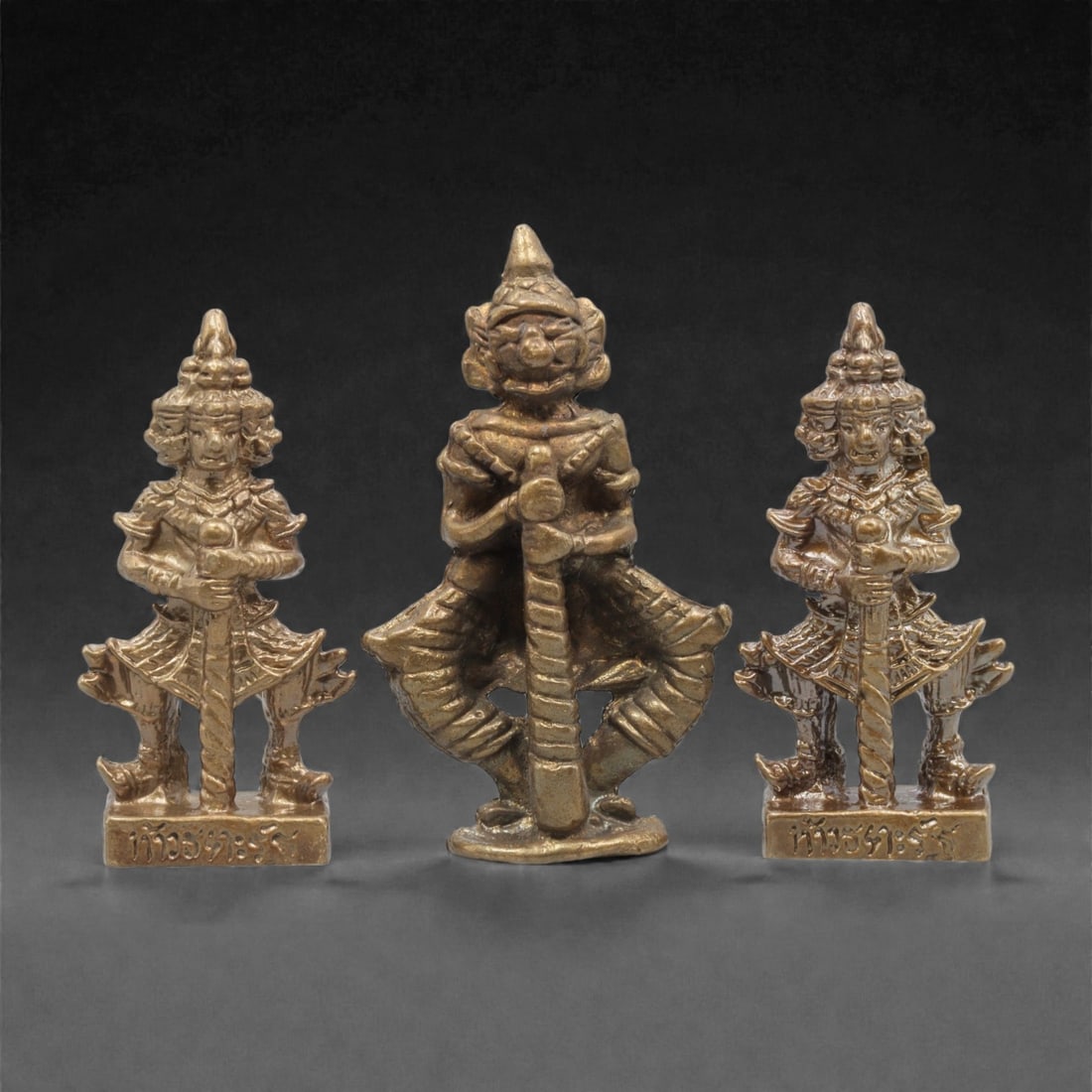Three Thai Bronze Guardian Miniature Figures, 20th Century, 17FM: Cast from bronze with a warm, aged patina, the set comprises three miniature guardian figures: two multi-headed figures with ornate headdresses and armor, and a single-headed guardian in a dynamic sta