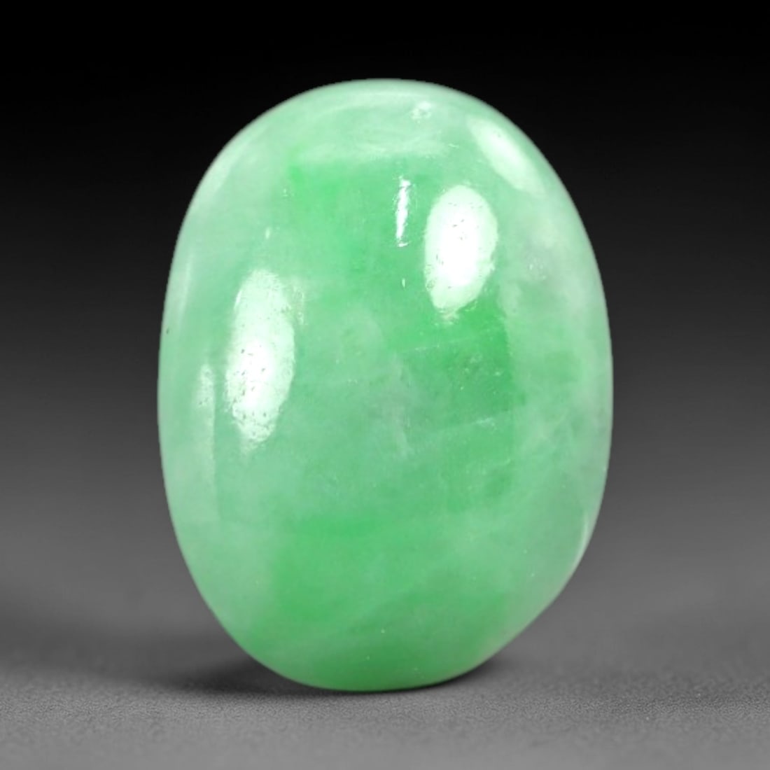 4.53 Carats Apple Green Jadeite Cabochon - Natural Burmese Stone, 88AB: This oval jadeite cabochon features a variegated apple green hue with concentrated verdant patches distributed across a semi-translucent matrix. The domed cabochon cut is calibrated to the stone's nat