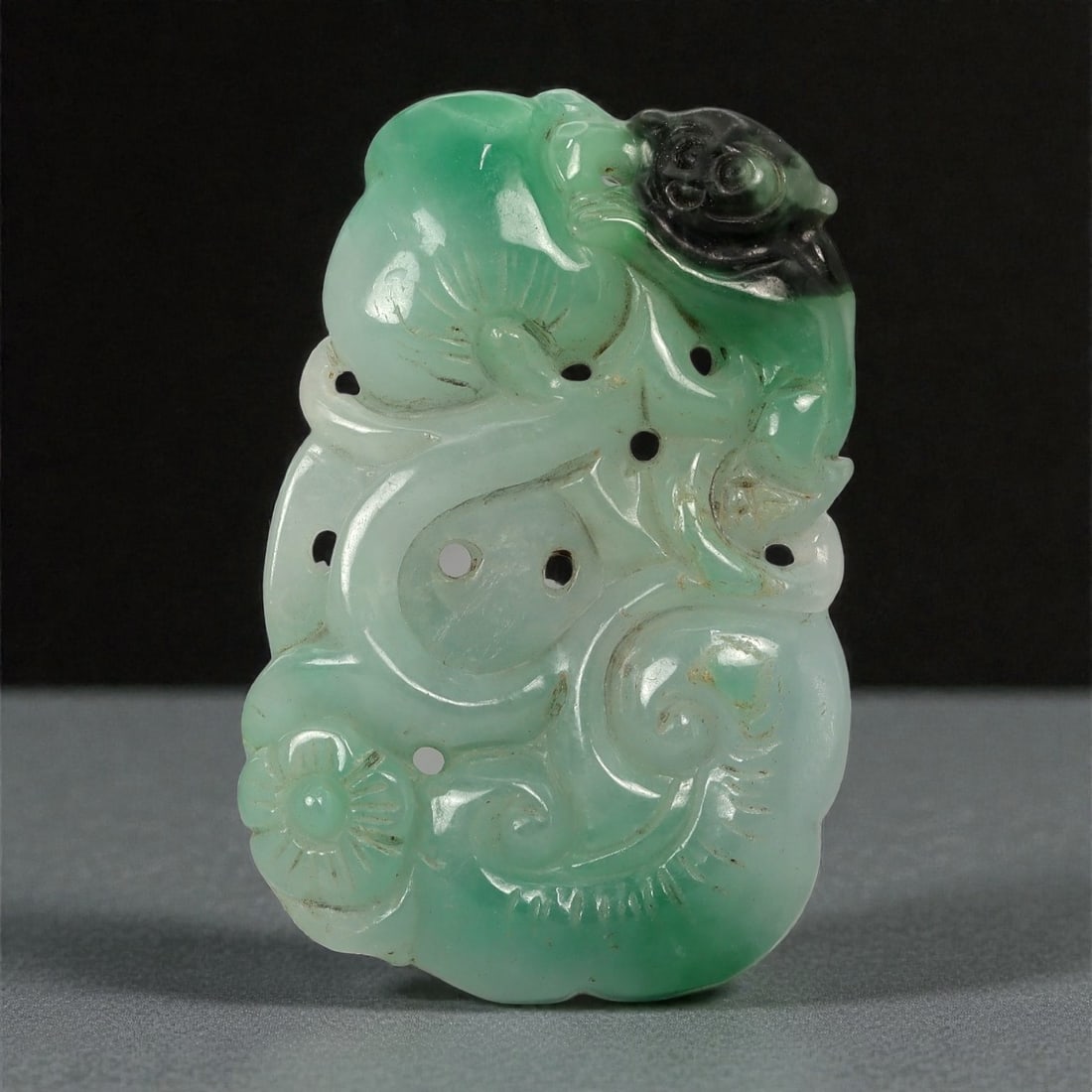 A Chinese Jadeite Jade Openwork Plaque, 20th Century, 91FC: Carved from pale green jadeite jade with areas of darker emerald-toned coloration and minor natural inclusions, the object is worked as an openwork plaque with an irregular vertical outline. The surfa