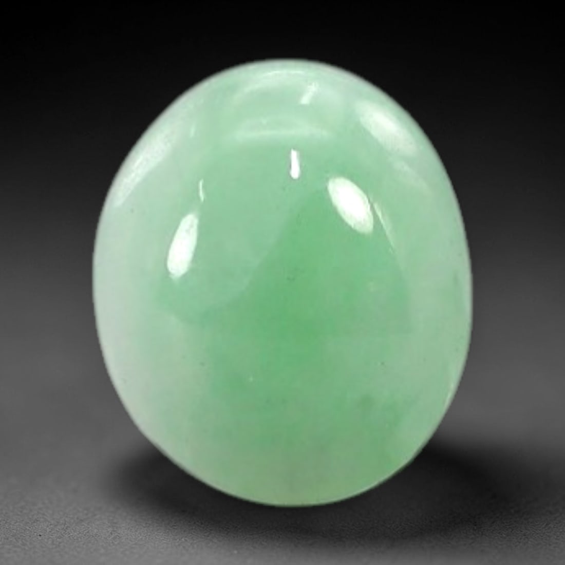 1.36 Carats Soft Mint Green Burmese Jadeite Jade Cabochon - Natural Loose Gemstone, 14AC: This oval Burmese jadeite jade cabochon exhibits a soft, uniform mint green hue, with a milky translucency that diffuses light evenly across its smooth, polished surface. The stone's even color distri