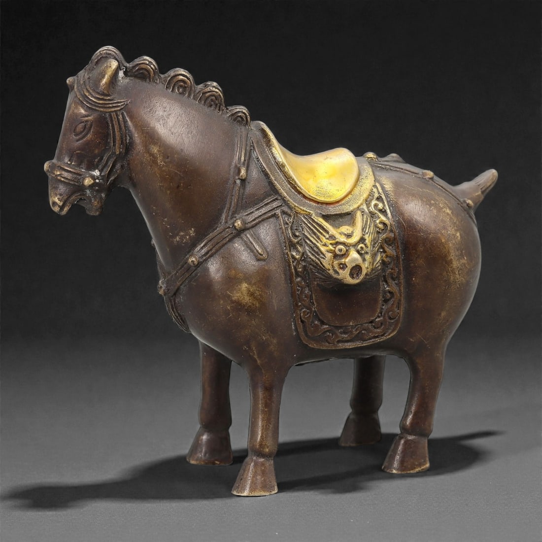 A Chinese Bronze Horse Effigy, 20th Century, 28FH: Cast in bronze as a standing horse, the figure is modeled with a compact body, straight legs terminating in simplified hooves, and a slightly lowered head with stylized facial features and incised man