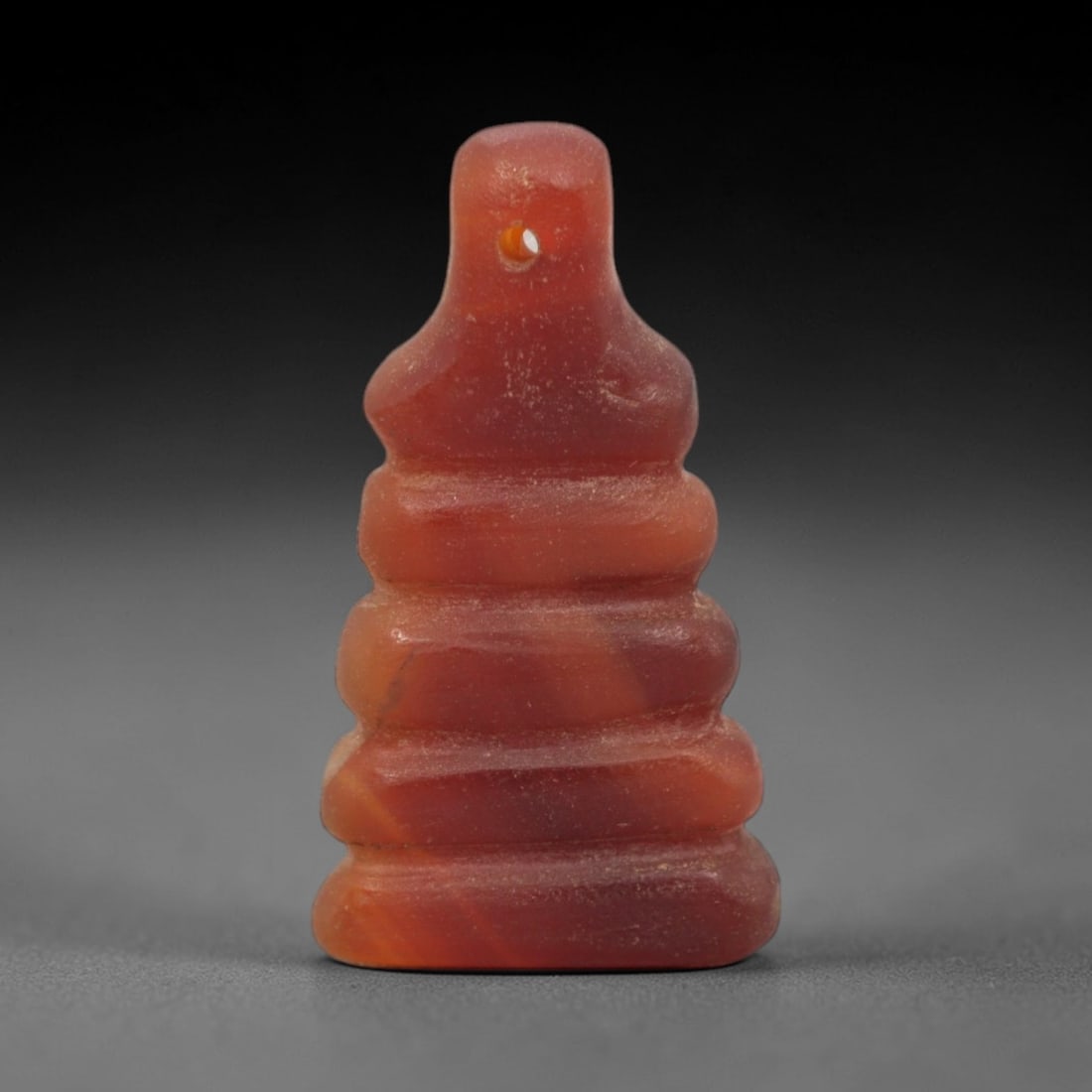 Ancient Carnelian Stacked - Egyptian Amulet Figurine, 64XS: Carved from rich, banded carnelian with natural surface patination and minor wear, this amulet takes the form of a stacked, tiered structure, featuring a narrow pierced upper tab and four rounded hori