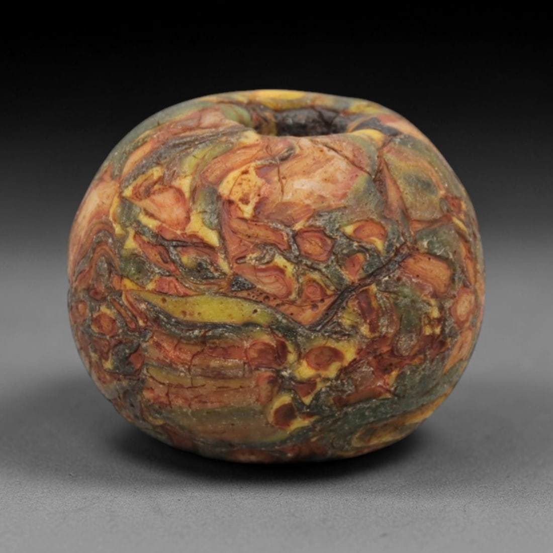 Ancient Islamic Glass Bead - Swirled Pattern Trade Bead, 52ZN: Crafted from ancient glass, this Islamic period bead features a swirled pattern of layered yellow, red, and white glass trails applied to a translucent base, characteristic of decorative glassmaking t
