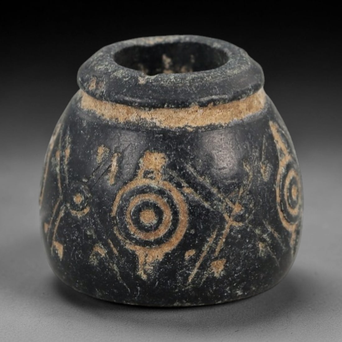 Ancient Stone Spindle Whorl - Near Eastern Concentric Dot Motif, 88XR: This ancient Near Eastern spindle whorl is crafted from stone, featuring incised concentric dot patterns radiating from the central perforation. The compact, rounded form is a traditional textile tool
