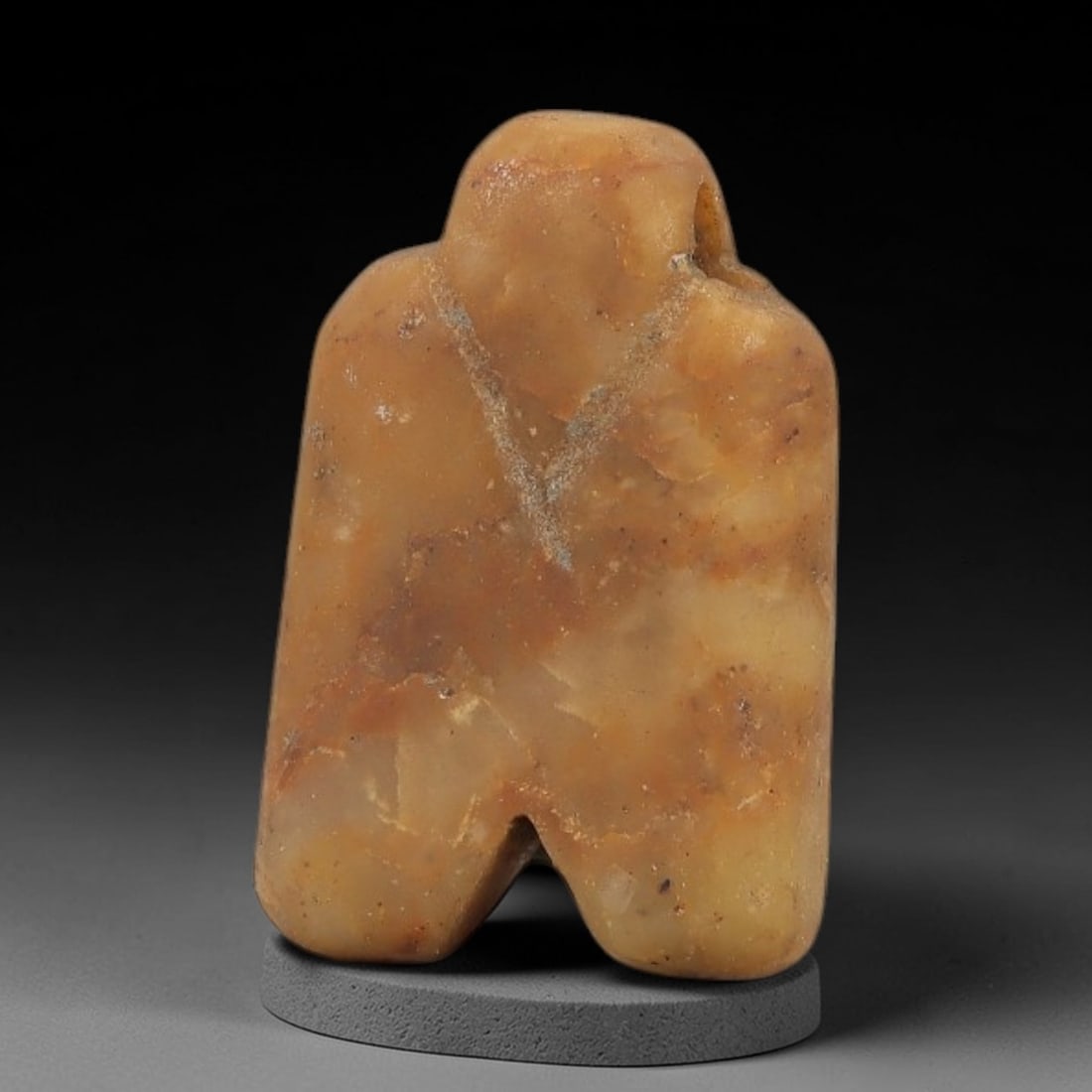 Ancient Egyptian Stone Amulet - Carved Ritual Pendant, 83AG: Carved from beige and light brown stone, this amulet features a stylized humanoid form with a central suspension loop at the top, consistent with ancient Egyptian ritual pendants of the Late Period. T
