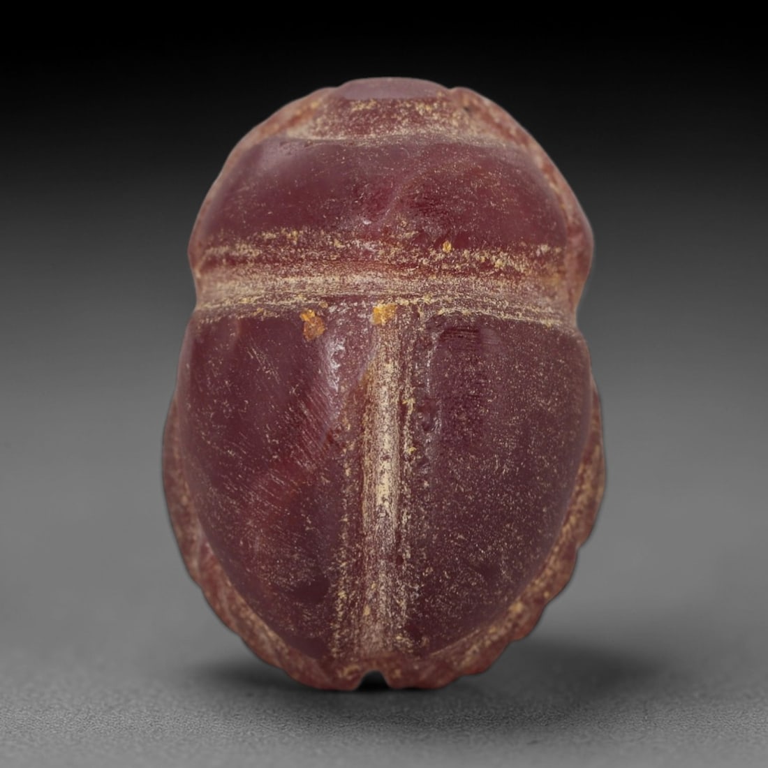 Ancient Carnelian Scarab Amulet - Egyptian Figurine, 35XS: Carved from rich, deep rose-red carnelian with subtle amber undertones, this amulet is formed as a stylized scarab beetle with incised linear detailing to define the head crest, central body ridge, an
