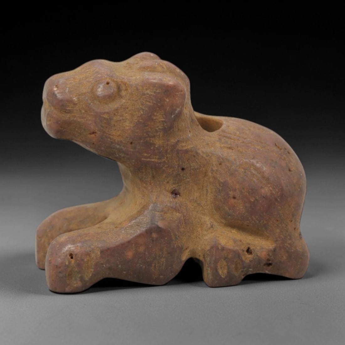 Ancient Stone Animal Amulet - Near Eastern Zoomorphic Pendant, 85XQ: This amulet is carved from a warm, reddish-brown stone, shaped into a stylized crouching animal form with a perforated suspension hole through the upper back, confirming its use as a wearable protecti
