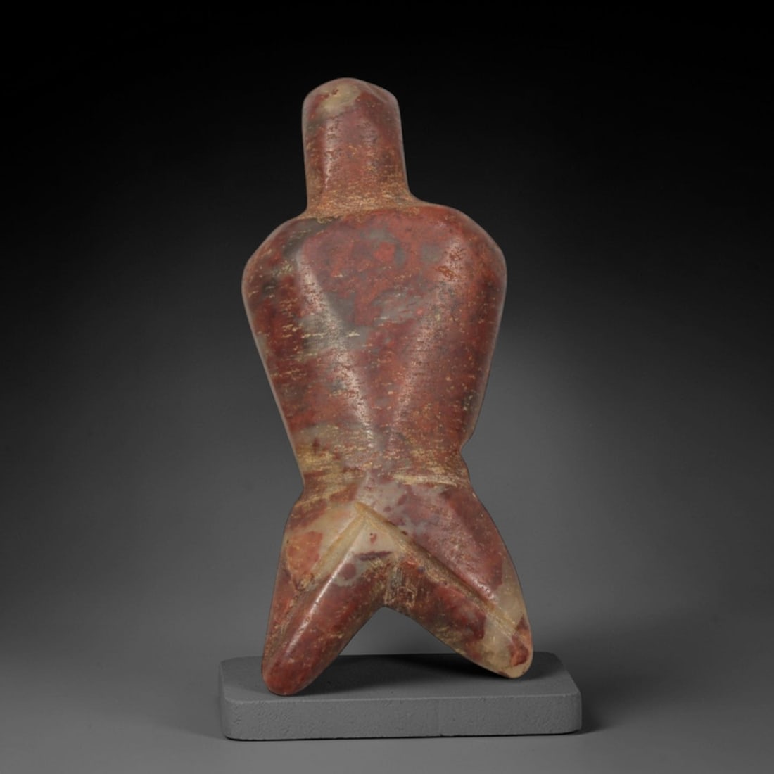 Ancient Red Stone Anthropomorphic Idol - Near Eastern Miniature Figurine, 81XP: Carved from a striking, variegated red stone with natural cream and grey inclusions, this miniature idol depicts a stylized humanoid figure in the iconic minimalist style of ancient Near Eastern ritua