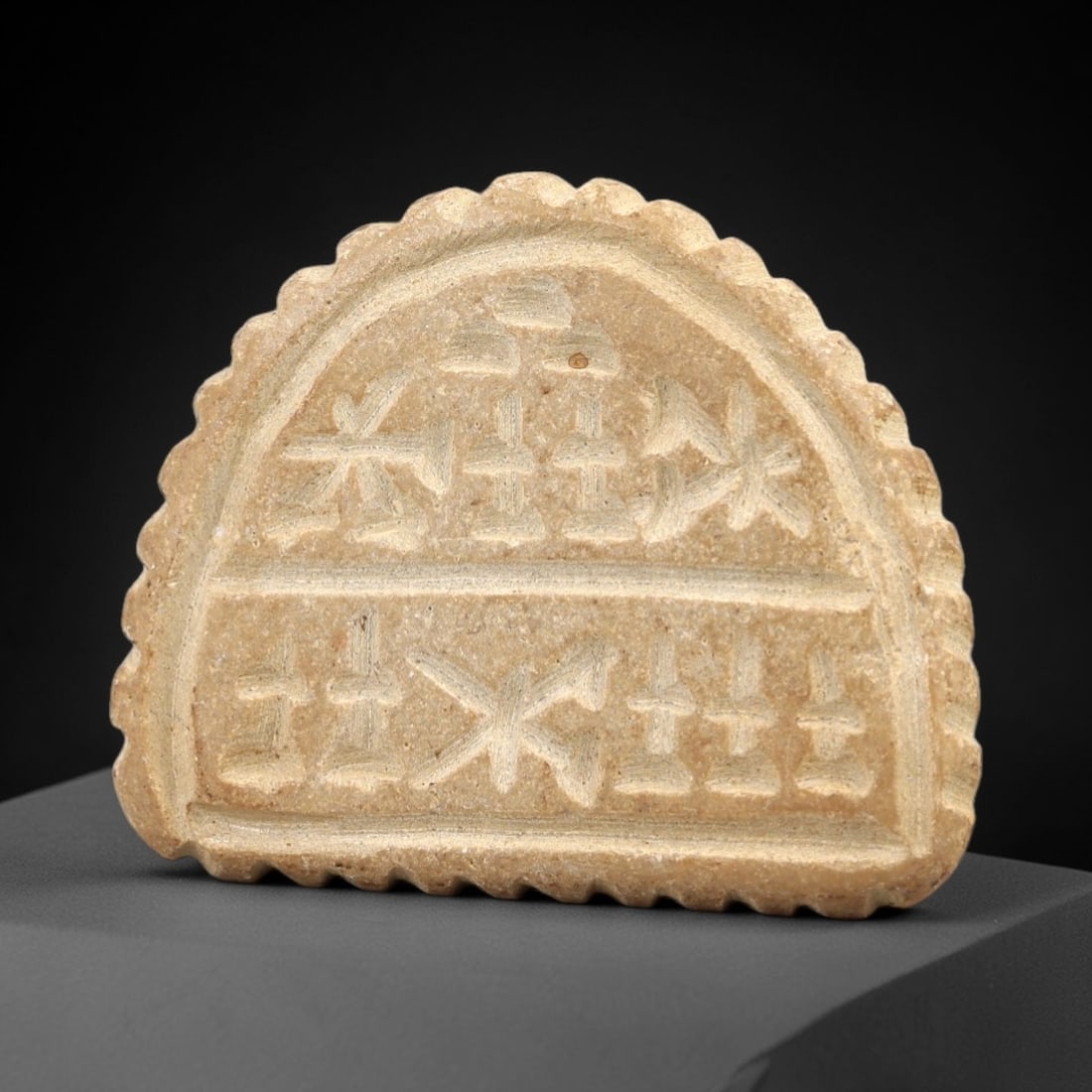 Ancient Stone Stamp Seal - Near Eastern Geometric Motif, 74AL: Carved from pale tan limestone, this semicircular stamp seal features a raised central handle with a suspension hole, confirming its function as a wearable amuletic seal. The impression face is divide