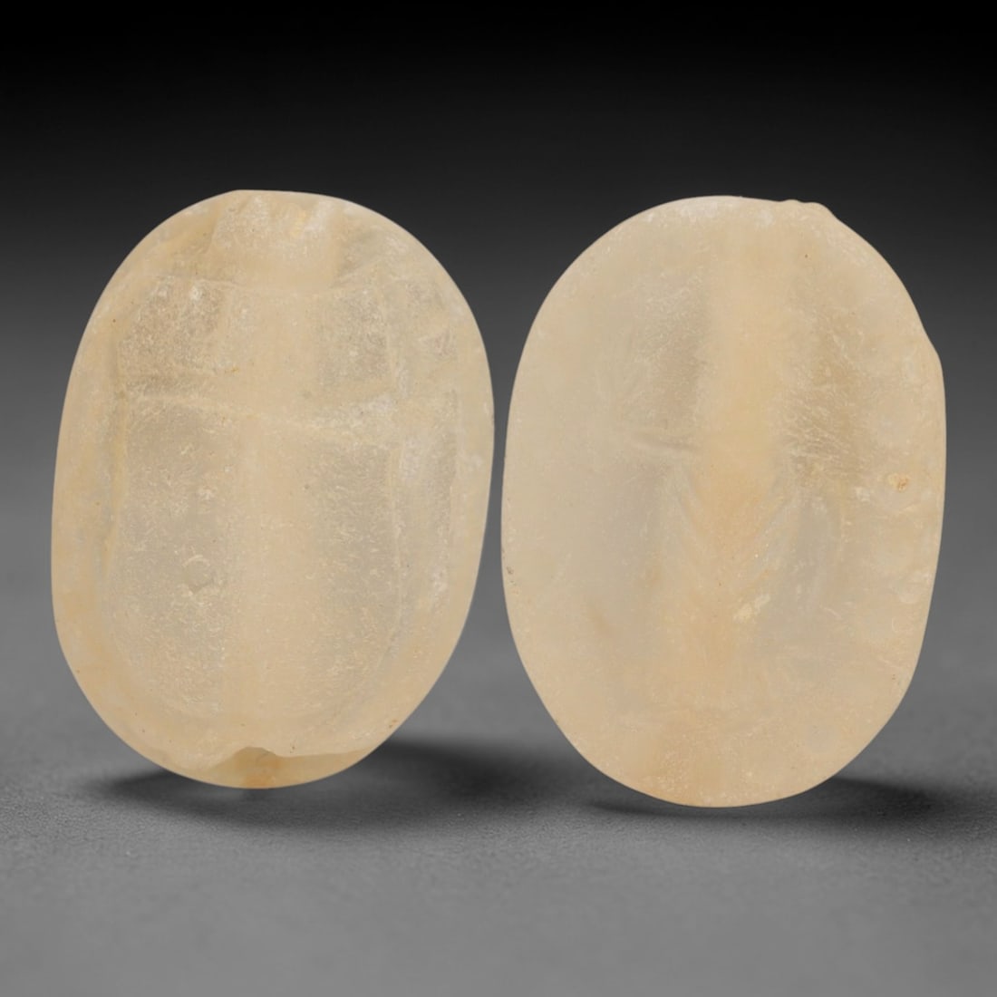 An Ancient Near Eastern Rock Crystal Scarab Stamp Seal, 1st Millennium BCE, 91AC: Carved from translucent rock crystal with a pale, milky patina and subtle internal inclusions, the object is formed as an oval scarab seal. The dorsal side is modeled in low relief with a simplified,