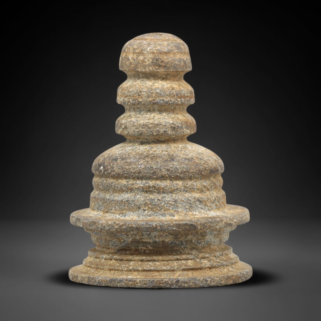 Ancient Buddhist Stone Stupa Votive - Figurine, 32ZR: This artifact is a carved stone votive stupa, crafted from a granular, grey-brown stone with a textured, weathered surface and natural earthy patina. The form follows the traditional Buddhist stupa ar