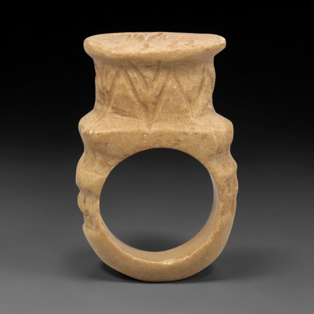 Ancient Stone Signet Ring - Near Eastern Pegasus, 41ZR: Carved from fine-grained tan stone with a matte, earthy patina, executed in a robust ring form characteristic of Near Eastern signet craftsmanship. The ring features a thick, circular band with incise