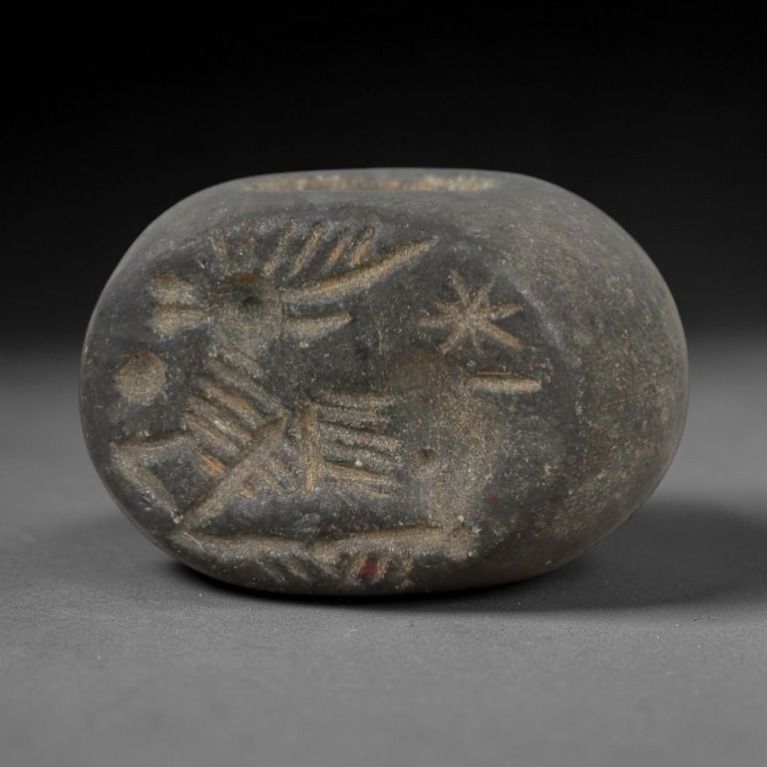 Ancient Dark Stone Stamp Seal - Near Eastern Animal Figure, 91AN: Carved from dense, dark grey stone, this hemispherical stamp seal displays incised iconography of a recumbent animal in profile, accompanied by a radiating sun motif and a star-like symbol. The animal