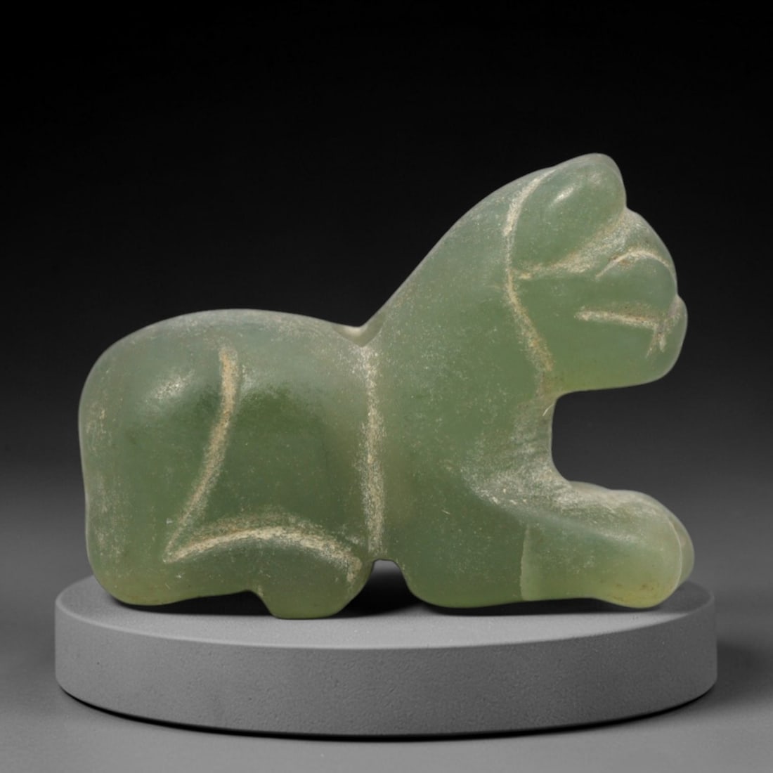 Ancient Serpentine Feline Amulet - Egyptian, 79ZW: Carved from serpentine, this amulet depicts a recumbent feline, a motif with protective and divine associations in ancient Egyptian culture. The piece features simplified incised detailing to denote t