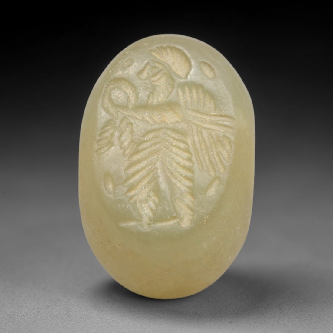Ancient Serpentine Hemispherical Stamp Seal - Near Eastern Winged Anthropomorphic Figure, 48ZS: Crafted from smooth, pale yellow-green serpentine stone, this hemispherical stamp seal bears incised carving of a winged anthropomorphic figure, depicted with a stylized headdress, defined facial prof