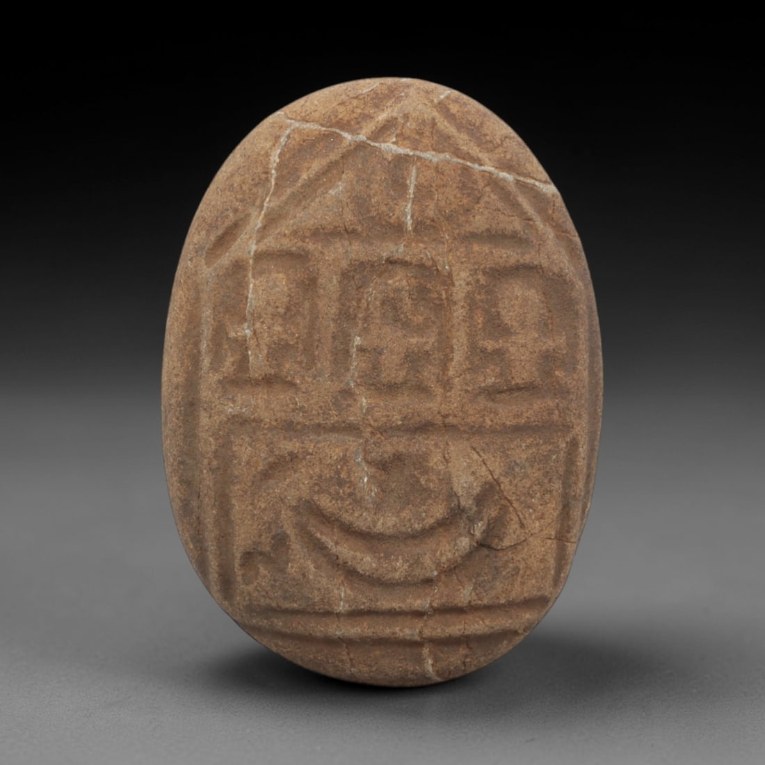 Ancient Stone Seal - Christian Era Religious Figurine, 48FX: Carved from a fine-grained, earthy stone, this oval seal features a divided iconographic scheme: the upper register displays three stylized, recessed figures within a geometric frame, while the lower