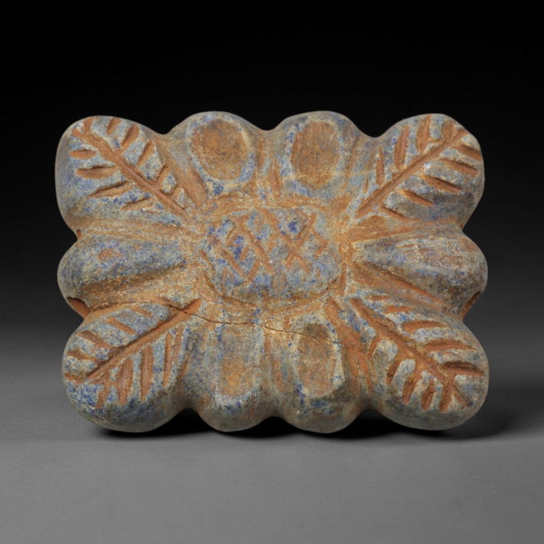 Ancient Lapis Lazuli Amulet - Near Eastern Palmiform Pendant, 60XP: Carved from rich blue lapis lazuli, this amulet features a symmetrical palmiform (palm-leaf) design with incised fronds radiating from a central geometric motif, a decorative pattern characteristic of